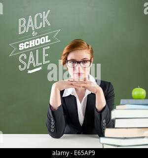 Composite image of redhead teacher sitting at desk Stock Photo