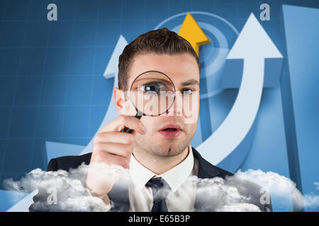 Composite image of businessman looking through magnifying glass Stock Photo