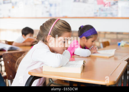 Cute pupils reading books at their desks Stock Photo