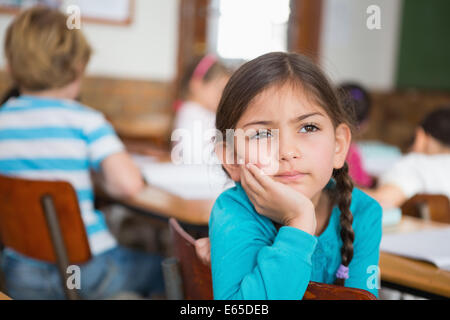 Thoughtful pupil sitting at her desk Stock Photo