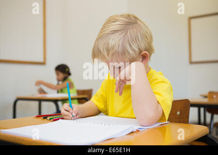 Cute pupils colouring at desks in classroom Stock Photo