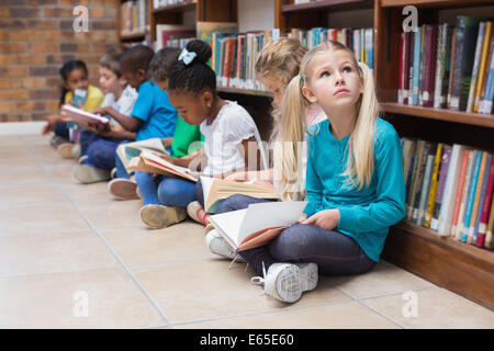 Cute pupils sitting on floor in library Stock Photo - Alamy