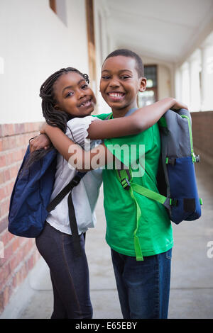 Cute pupils smiling at camera in corridor Stock Photo