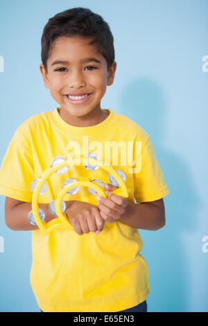 Cute little boy playing the tambourine in classroom Stock Photo