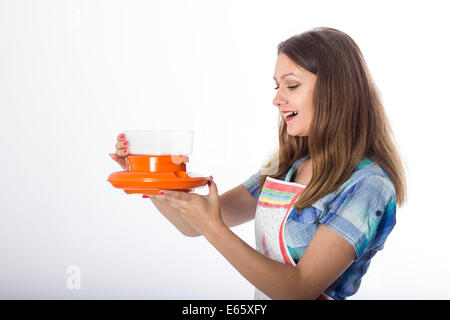 Young brunette female cook playfully prepares food using kitchen utensils Stock Photo