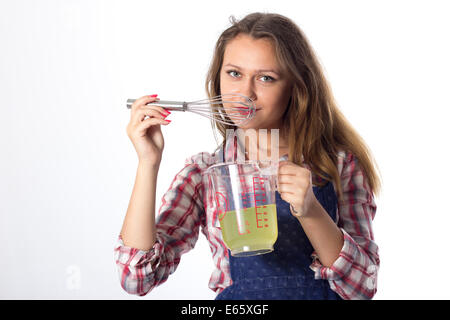 Young brunette female cook playfully prepares food using kitchen utensils Stock Photo