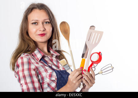 Young brunette female cook playfully prepares food using kitchen utensils Stock Photo