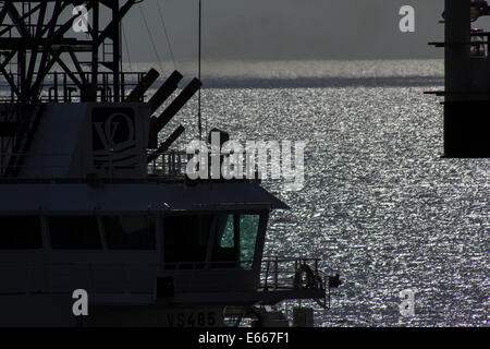 A North Sea Supply Boat alongside a drilling rig in the late afternoon sun Stock Photo