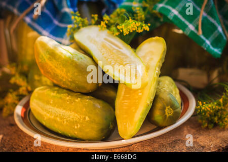 Chopped pickled cucumbers on a plate on a wooden board Stock Photo