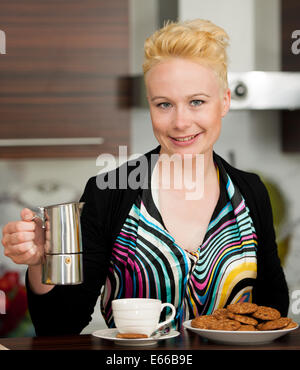 beautiful young caucasian blond woman cooking espresso coffee in cosy kitchen Stock Photo