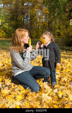 Happy family: young mother with her little girl making a walk in autumn. Stock Photo