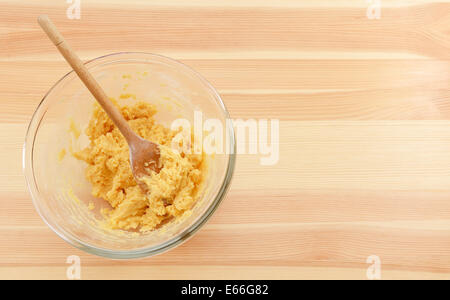 https://l450v.alamy.com/450v/e66g82/bowl-of-raw-cookie-dough-with-a-mixing-spoon-on-a-wooden-table-e66g82.jpg