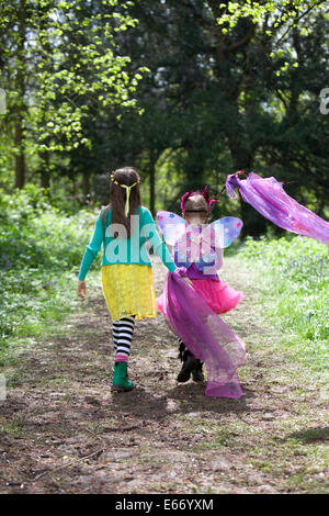 Two young girls in brightly coloured clothes, walking along a path through an English woodland. Stock Photo