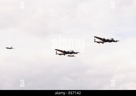 Kent, UK. 16th Aug, 2014. A fly-over by the only two airworthy Avro Lancaster Bombers left from WW2 in formation with two Spitfires at the 6th Annual Combined Ops Show at Headcorn Airfield. Featuring fly-overs, war re-enactments, fancy dress, actual and replica memorabilia, and more. Credit:  Tom Arne Hanslien/Alamy Live News Stock Photo