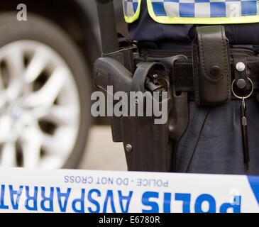 Gun in a gun belt of a Swedish policeman while standing behind the line that has sealed off public entrance.