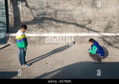 Two young boys playing outdoors in a Beijing hutong Stock Photo