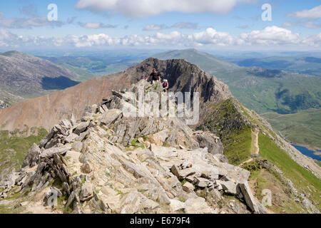 Hikers scrambling on Crib y Ddysgl with view back to Crib Goch ridge on Snowdon Horseshoe in Snowdonia North Wales UK Stock Photo