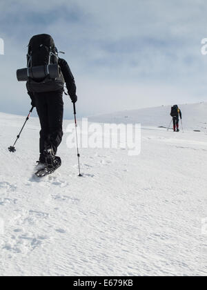 two men with heavy backpacks snowshoeing in winter mountain landscape. Huldraheimen, Gausdal Westfjel, Norway Stock Photo