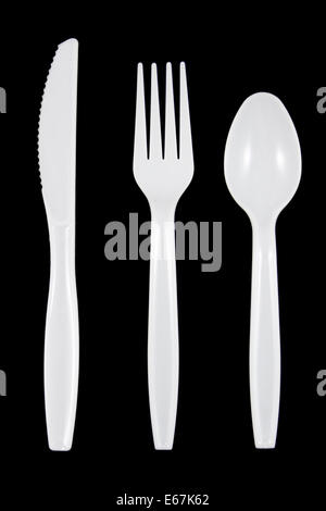 White plastic knife, fork and spoon on black background. Stock Photo