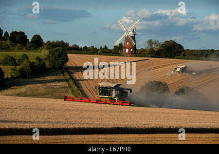 Harvest Time in Thaxted Essex England UK. 17 August 2014 Combine harvester brings in the last of the milling wheat from Simon Latham's farm in Thaxted in north Essex in England amid fine weather. The scene is made picture perfect with Thaxted Church and the ancient John Webbs Windmill in the background in the golden autumn evening light. Credit:  BRIAN HARRIS/Alamy Live News Stock Photo