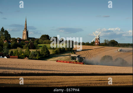 Harvest Time in Thaxted Essex England UK. 17 August 2014 Combine harvester brings in the last of the milling wheat from Simon Latham's farm in Thaxted in north Essex in England amid fine weather. The scene is made picture perfect with Thaxted Church and the ancient John Webbs Windmill in the background in the golden autumn evening light. Credit:  BRIAN HARRIS/Alamy Live News Stock Photo