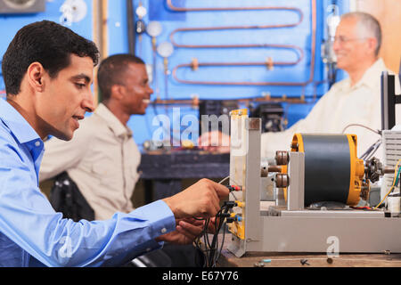 Student setting up generator experiment while instructor discusses HVAC system to student in wheelchair Stock Photo