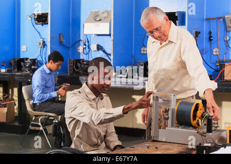 Student in wheelchair setting up generator experiment with professor while student examines HVAC system Stock Photo