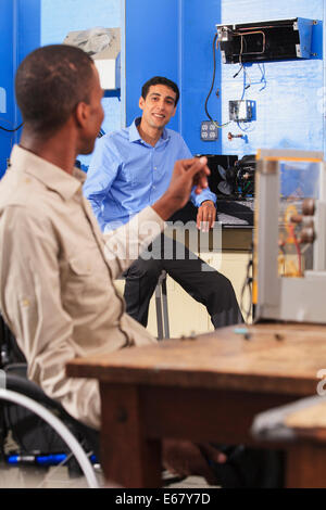 Student in wheelchair setting up generator experiment and talking to student in HVAC classroom Stock Photo