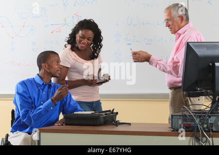 Engineering students, one in wheelchair, discussing electronic components with Professor Stock Photo
