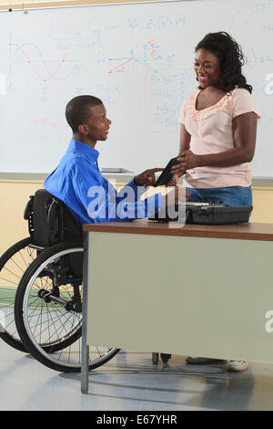 Two engineering students, one in wheelchair, looking at electronic tablet in a classroom Stock Photo