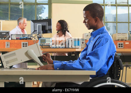 Engineering students in an electronics classroom, one in a wheelchair adjusting an oscilloscope Stock Photo