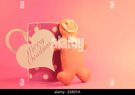 Merry Christmas ginger bread man with pink polka dot cup of coffee or tea mug and heart gift tag Stock Photo