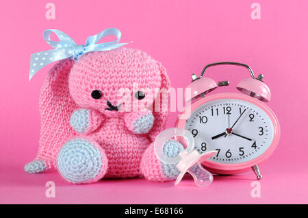 Baby girl nursery cute bunny toy, dummy pacifier and clock for on pink background baby shower or newborn girl greeting card. Stock Photo