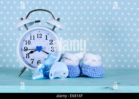Baby boy nursery blue and white booties and clock, on aqua vintage shabby chic wood table and polka dot background Stock Photo