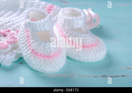 Baby girl nursery pink and white stripe wool booties, bonnet and pacifier dummy close up. Stock Photo
