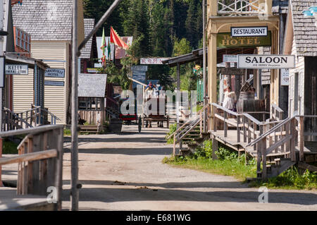 People tourists riding stagecoach on main street historic wooden buildings gold rush town Barkerville, British Columbia, Canada. Stock Photo