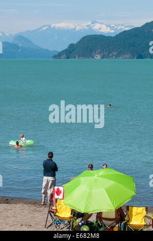 Green beach umbrella family on beach at Harrison Lake, Harrison Hot Springs resort, British Columbia, Canada. Stock Photo