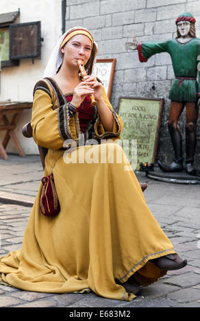 TALLINN, ESTONIA - JULY 31, 2014: Young girl in traditional costume playing flute in Tallinn old town, Estonia. Stock Photo