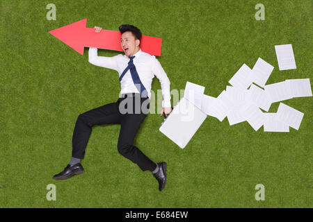 Young man holding briefcase lying on grass Stock Photo