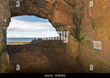 SCULPTORS CAVE  MORAY COAST SCOTLAND NEAR HOPEMAN ENTRANCE AND INTERIOR WALL WITH EXPLANATORY SIGN AND THE PICTISH CARVINGS Stock Photo