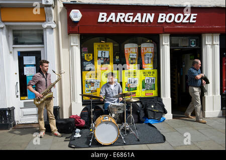 Saxophone & drums duo buskers on the street outside Bargain Booze during Brecon Jazz Festival 2014 Stock Photo