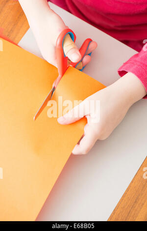 Little girl cutting paper with scissors Stock Photo