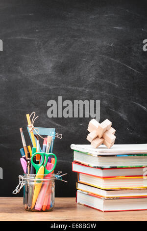 School accessories on desktop with blank blackboard in the background Stock Photo