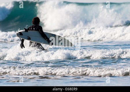 Surfer getting past the break on Porthtowan Beach, Cornwall UK. Stock Photo