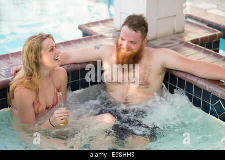 Jacuzzi in wellness area of hotel with young adults drinking beer and laughing. Stock Photo