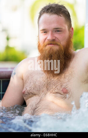 Caucasian man with long red beard is enjoying a jet stream bath in a hot tub. Stock Photo