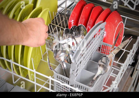 close-up of male hands lodaing dirty dishes to the dishwashing machine Stock Photo