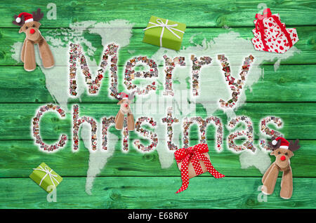 Merry Xmas greetings with text on green wooden background - letters of different xmas images. Stock Photo