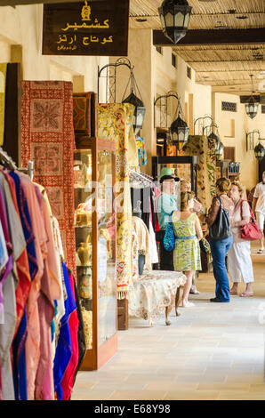 Shopping for clothes clothing souvenirs and textiles at the Souk Madinat Jumeirah market Dubai, United Arab Emirates UAE. Stock Photo