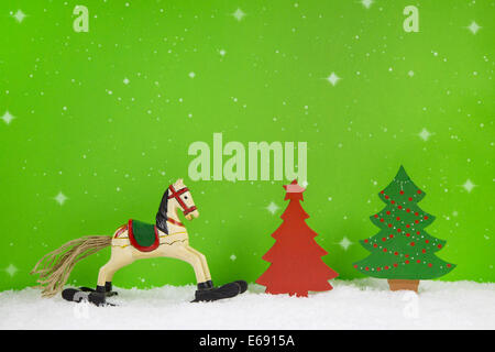 Rocking horse and red christmas tree on green background for decorations. Stock Photo